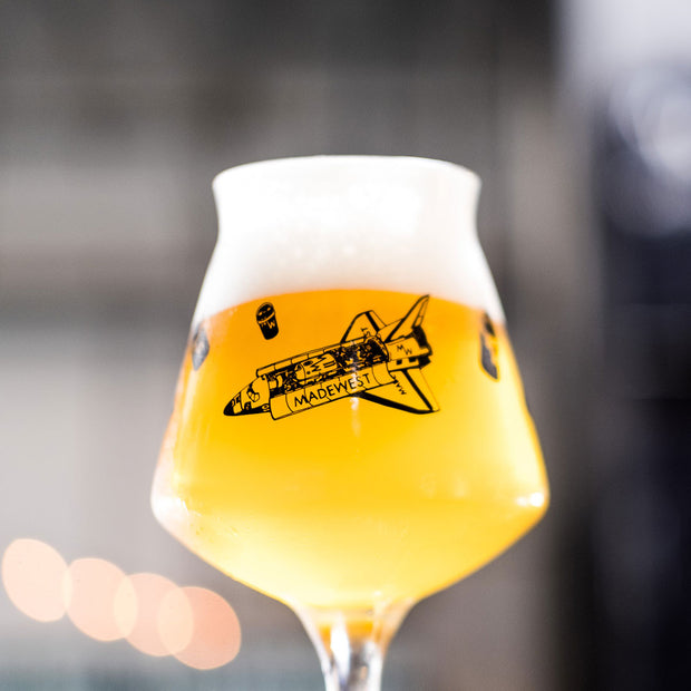 close up picture of stemmed beer glass with an illustration of a space shuttle on the side.